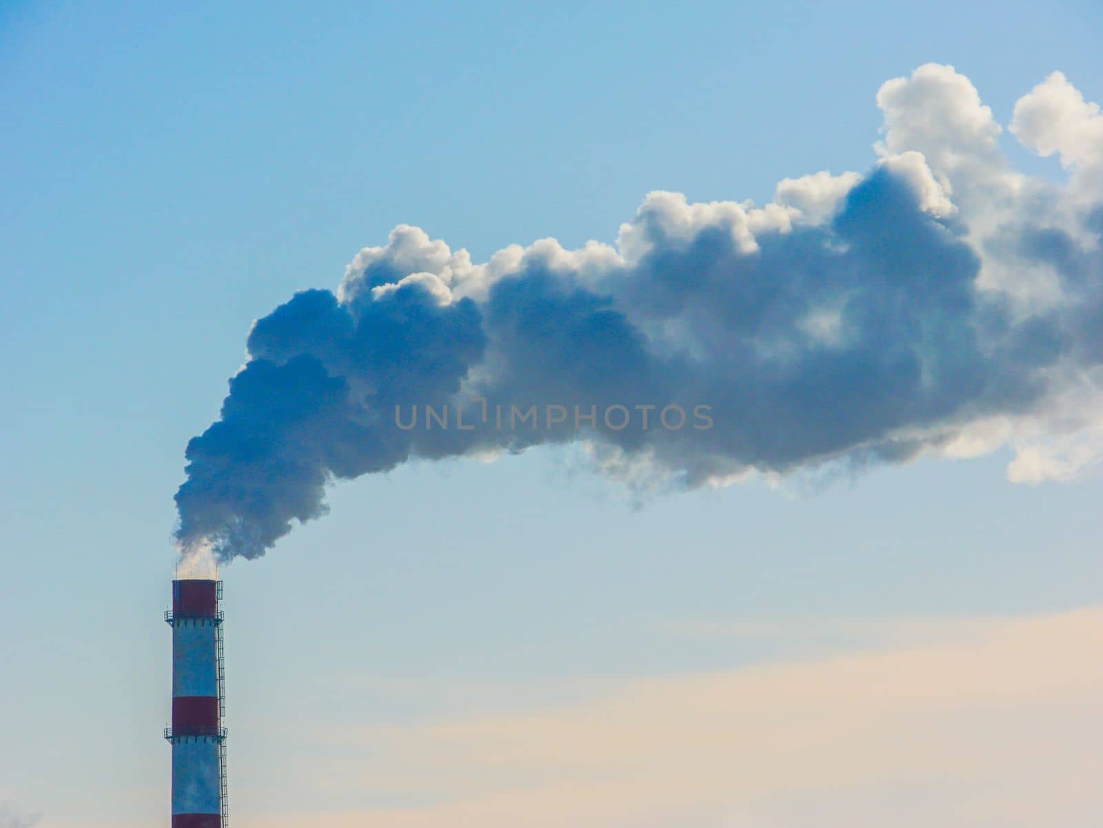 High chimney with thick smoke on the background of the sky.Factory smoke. Smoke pollution of the environment.