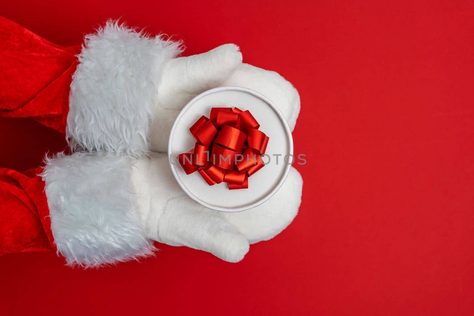 Santa's hands are holding a gift for Christmas. red background with space to copy. Christmas time