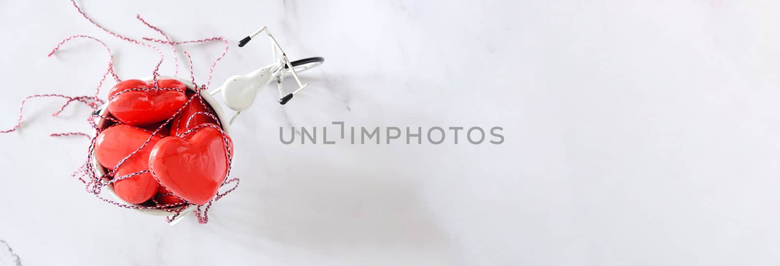 red toy hearts in the back of a white mini bike on a white wooden background Valentine's Day concept banner. High quality photo