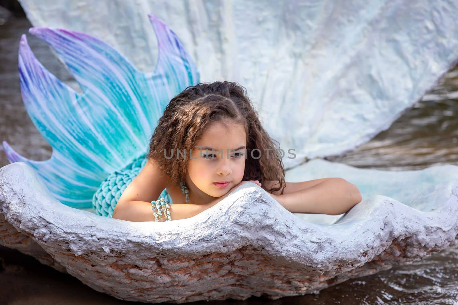 A beautiful girl in a turquoise mermaid costume in a large sea shell by Zakharova