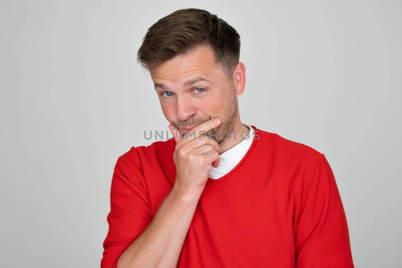 Thinking man looking up rubbing his chin isolated on gray background. Casual young pensive businessman looking up at copyspace. 