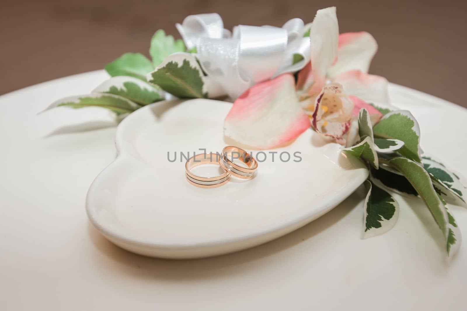 Wedding rings on a white saucer by Dustick