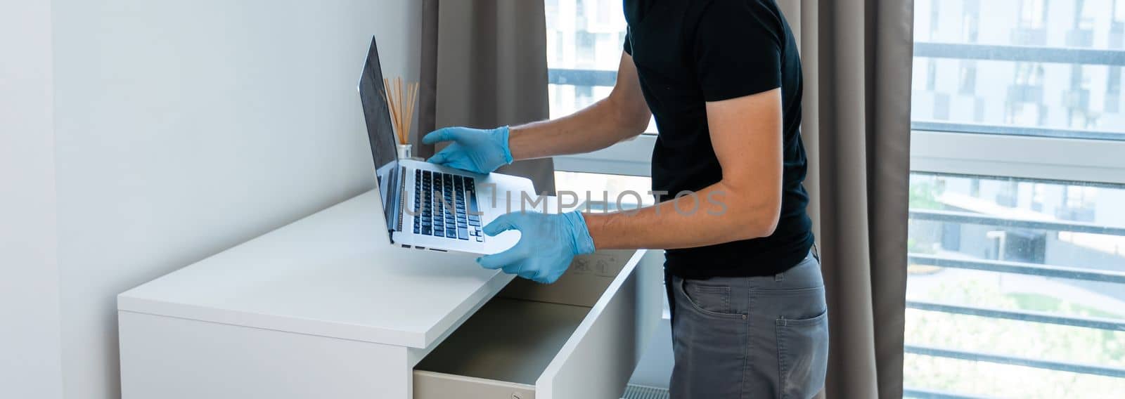 Thief with black balaclava stealing laptop. The burglar commits a crime in Luxury apartment.