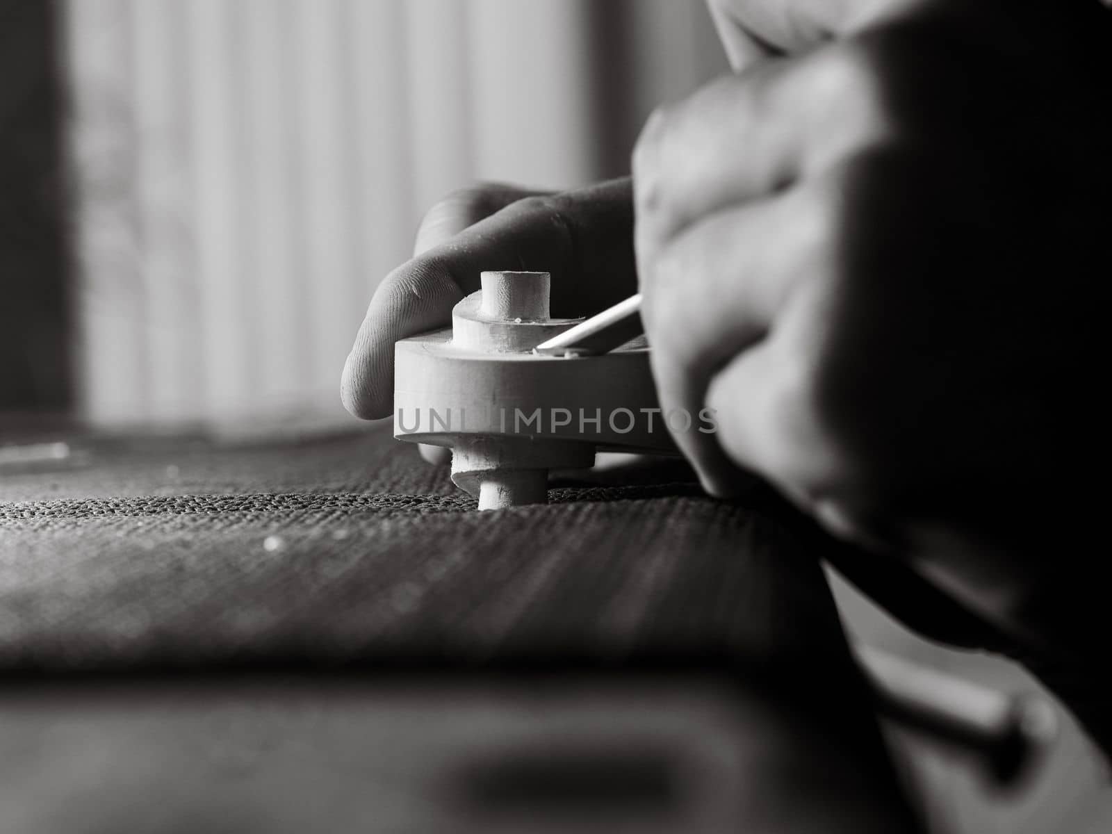 violinmaker working on a handmade contemporary stringed instrument scroll
