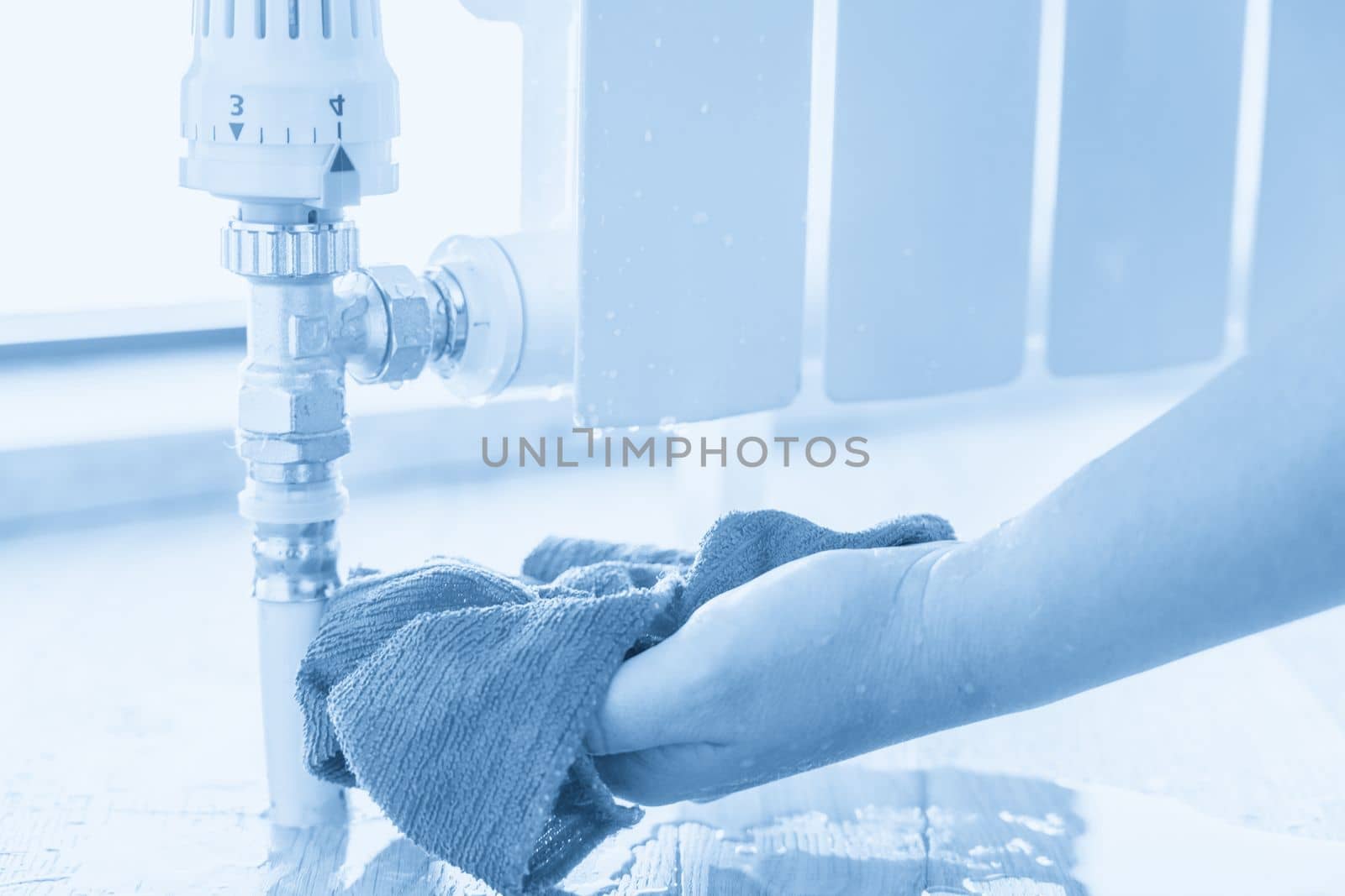Female hand with rag cleaning water from heating radiator