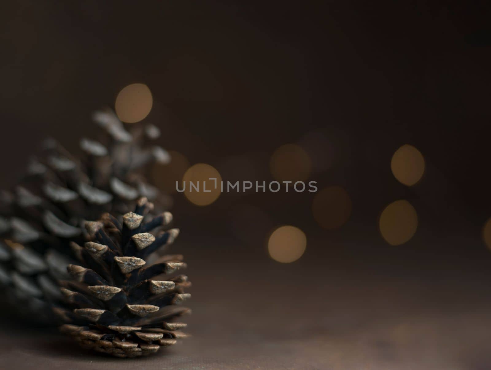 Pine cone isolated on light background. Holiday glowing backdrop. Defocused background with blinking light. Blurred Bokeh. copy space. by Costin