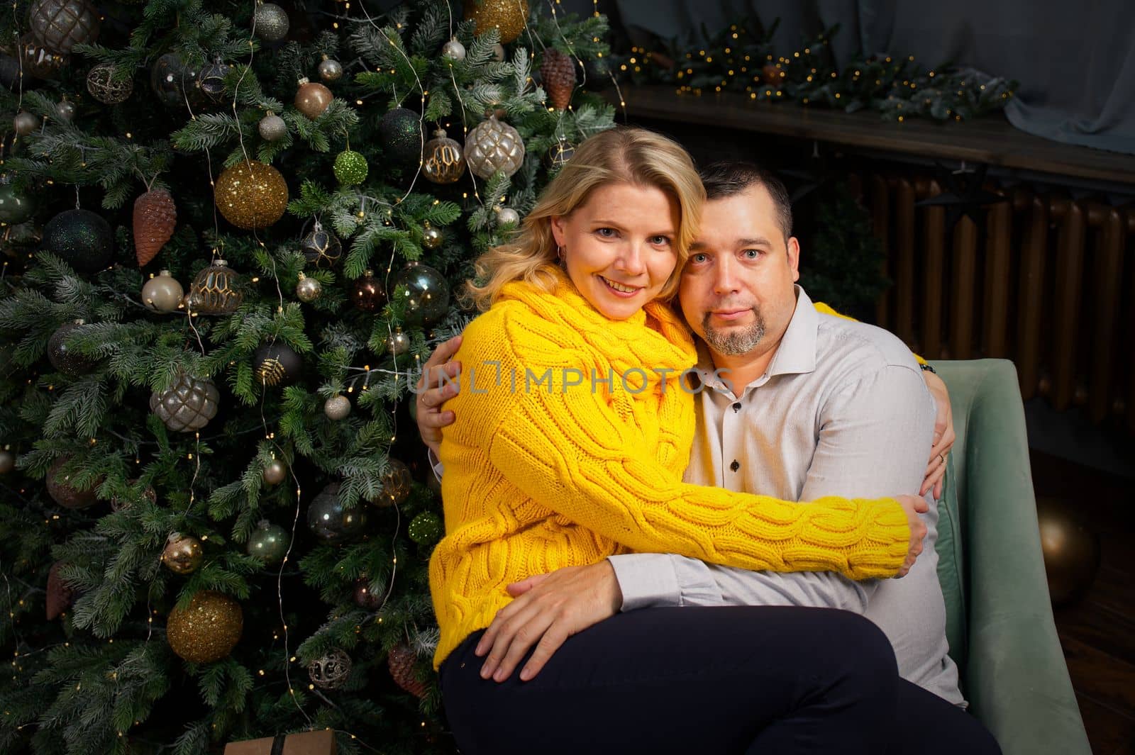 cute couple sitting near the christmas tree. Celebrating christmas and new year together. Happy man and woman enjoy winter holiday together.