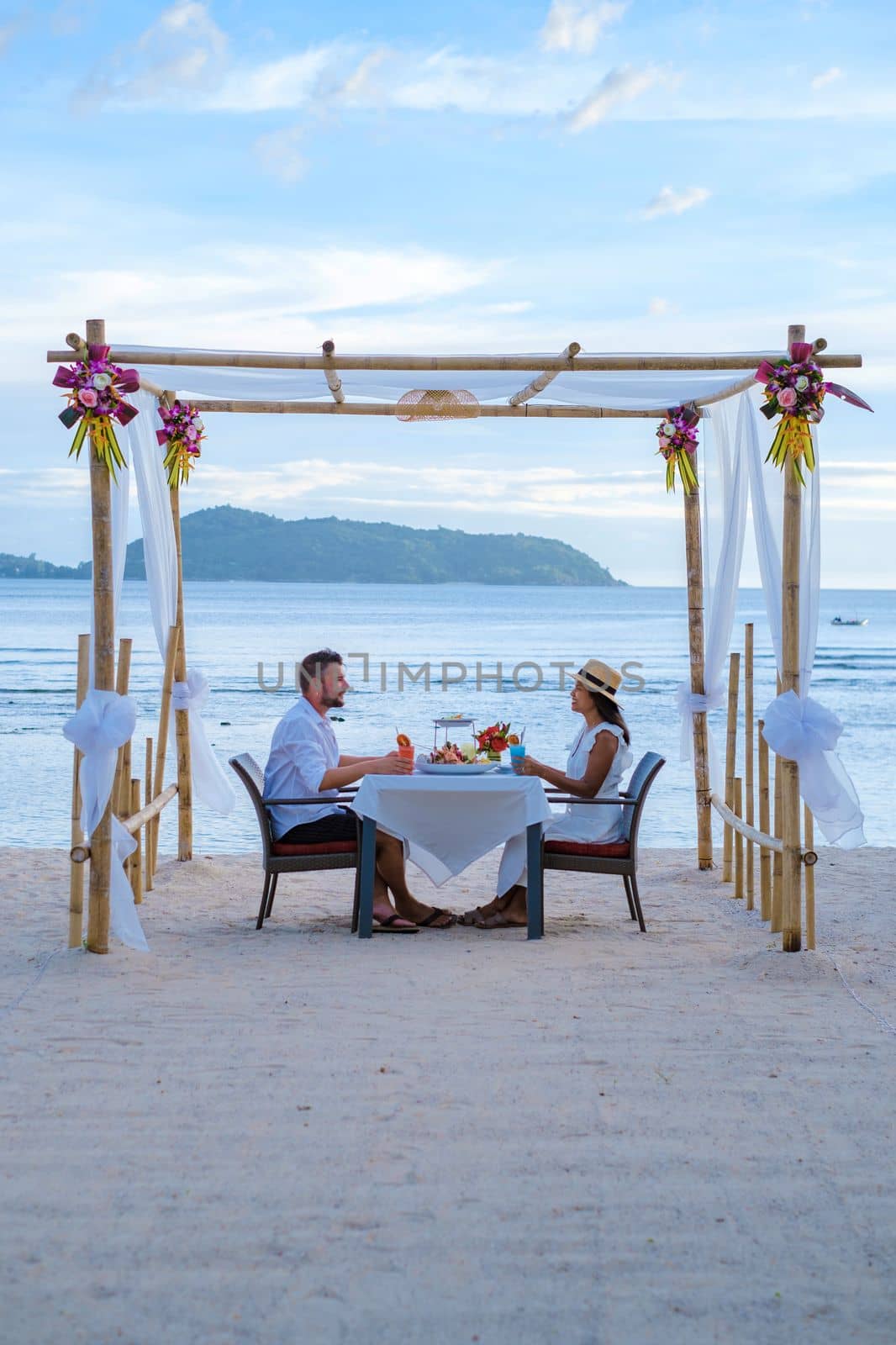 Romantic dinner on the beach in Phuket Thailand, couple man and woman having dinner on the beach  by fokkebok
