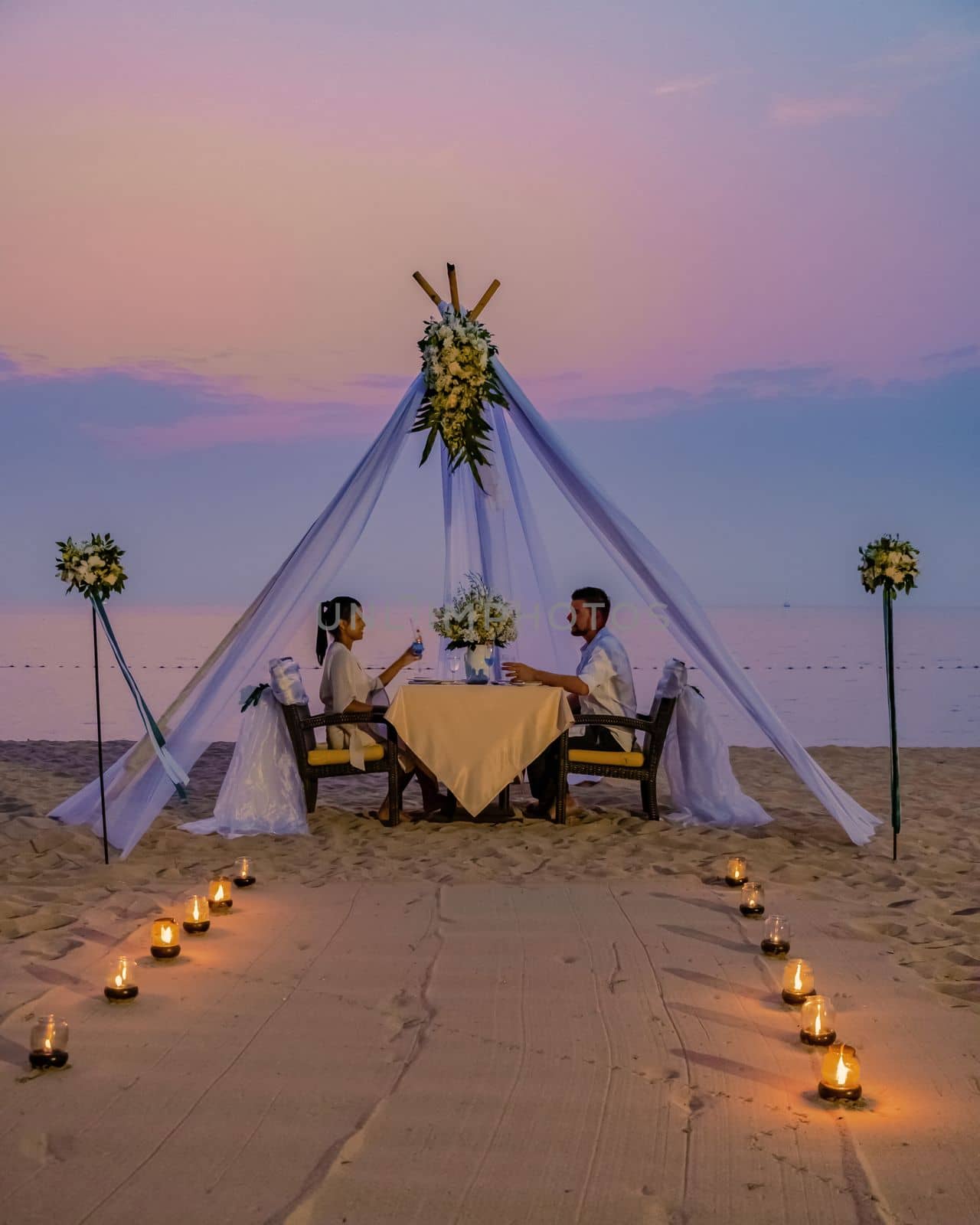 Romantic dinner on the beach in Phuket Thailand, couple man and woman having dinner on the beach  by fokkebok