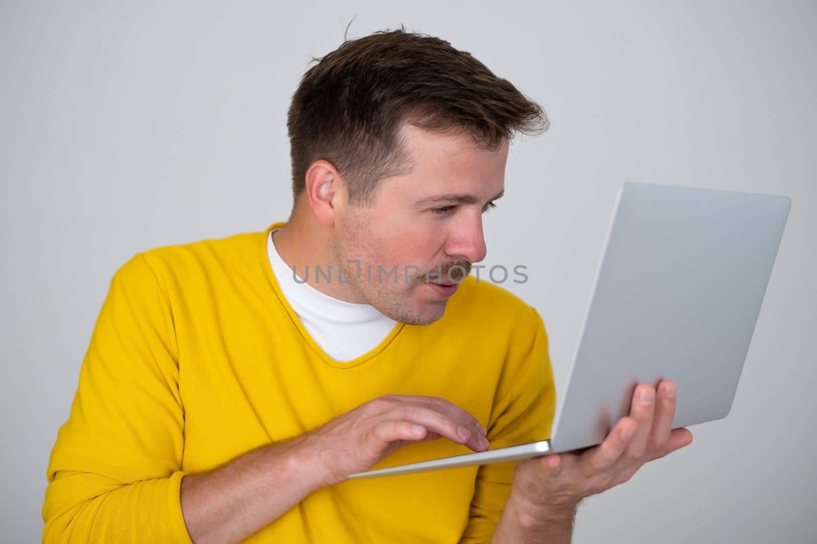 Thoughtful focused clever interested freelancer holding laptop with hands working on deadline project isolated grey color background. 