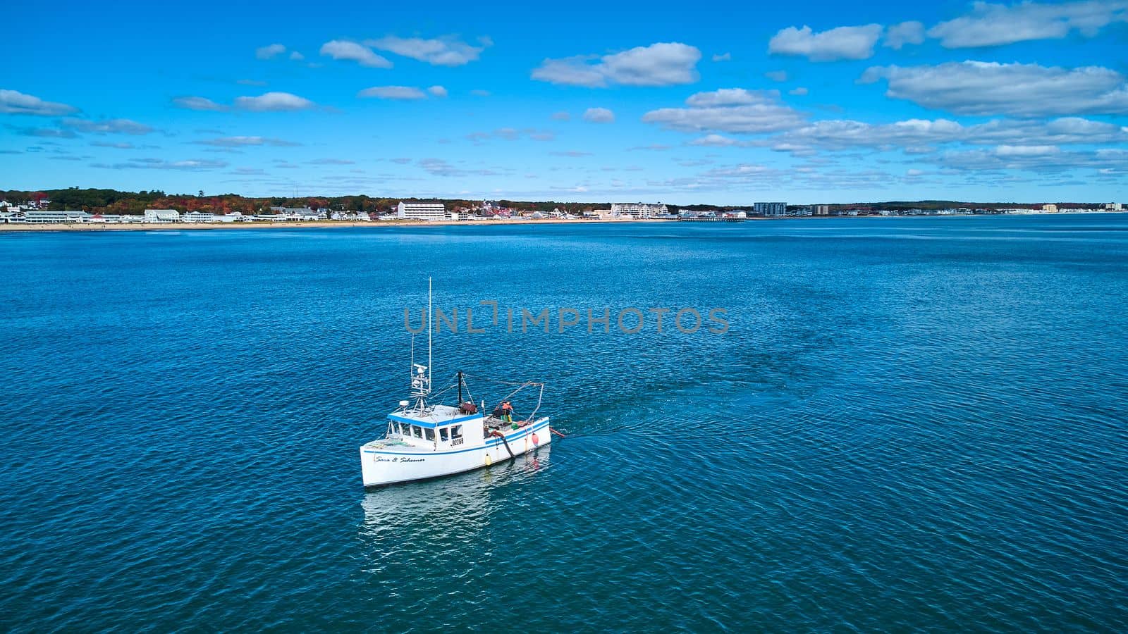 Fishing boat off coast of Maine with distant view of coast by njproductions