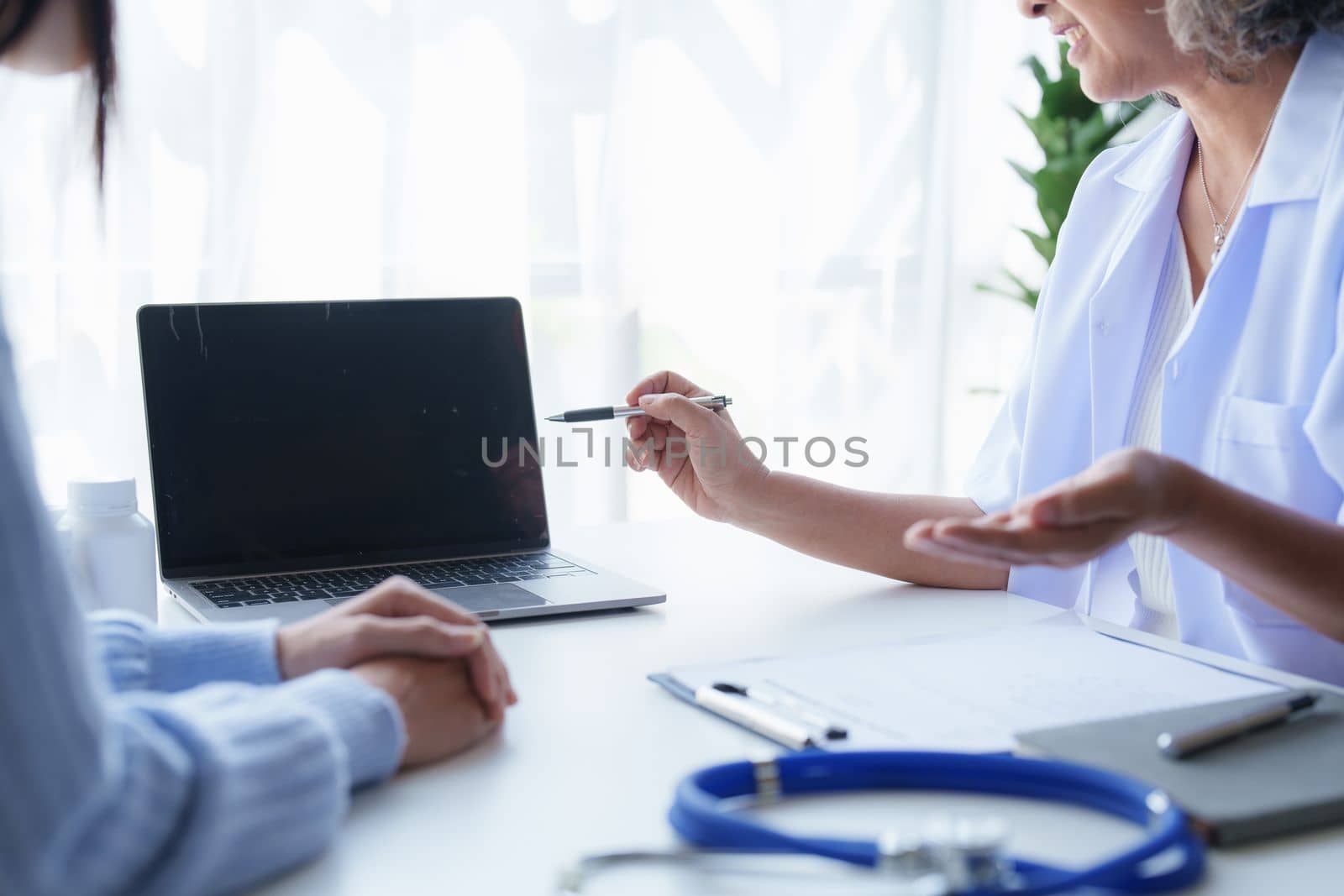 Doctor having conversation with patient while discussing explaining symptom and hold hand for encourage.