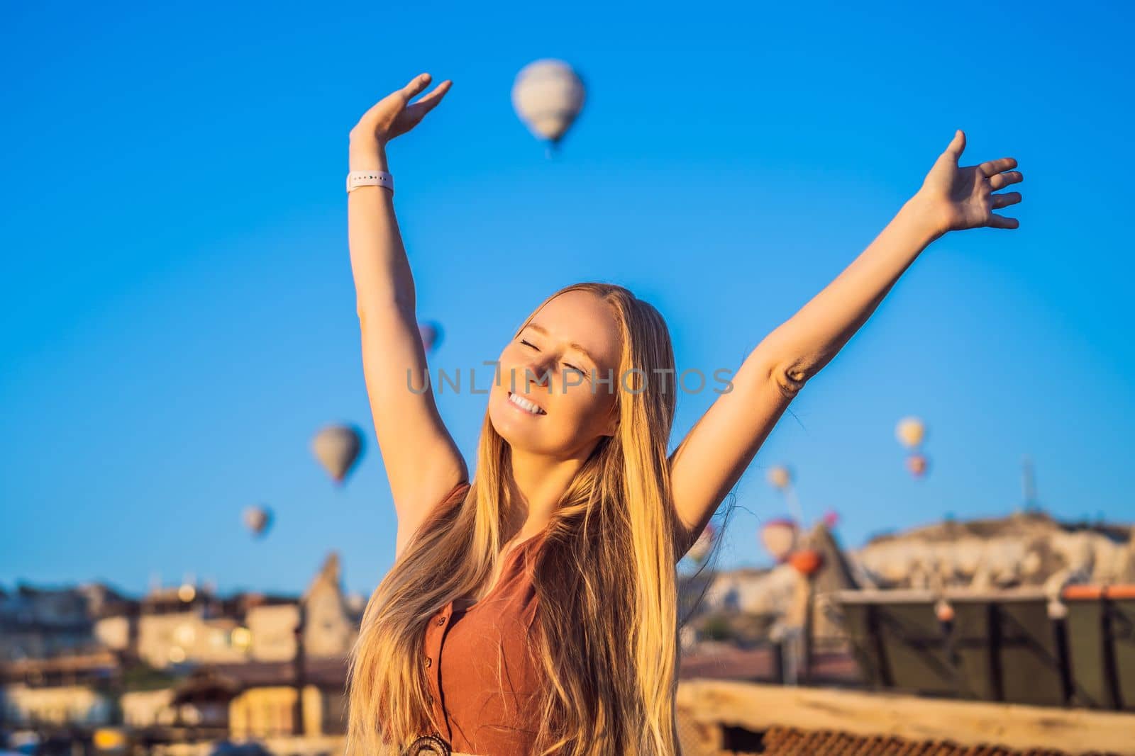 Tourist woman looking at hot air balloons in Cappadocia, Turkey. Happy Travel in Turkey concept. Woman on a mountain top enjoying wonderful view.