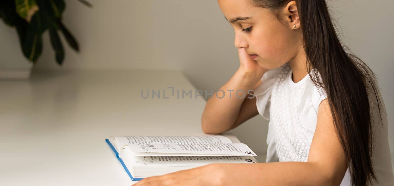 education and school concept - little student girl studying and reading book at school