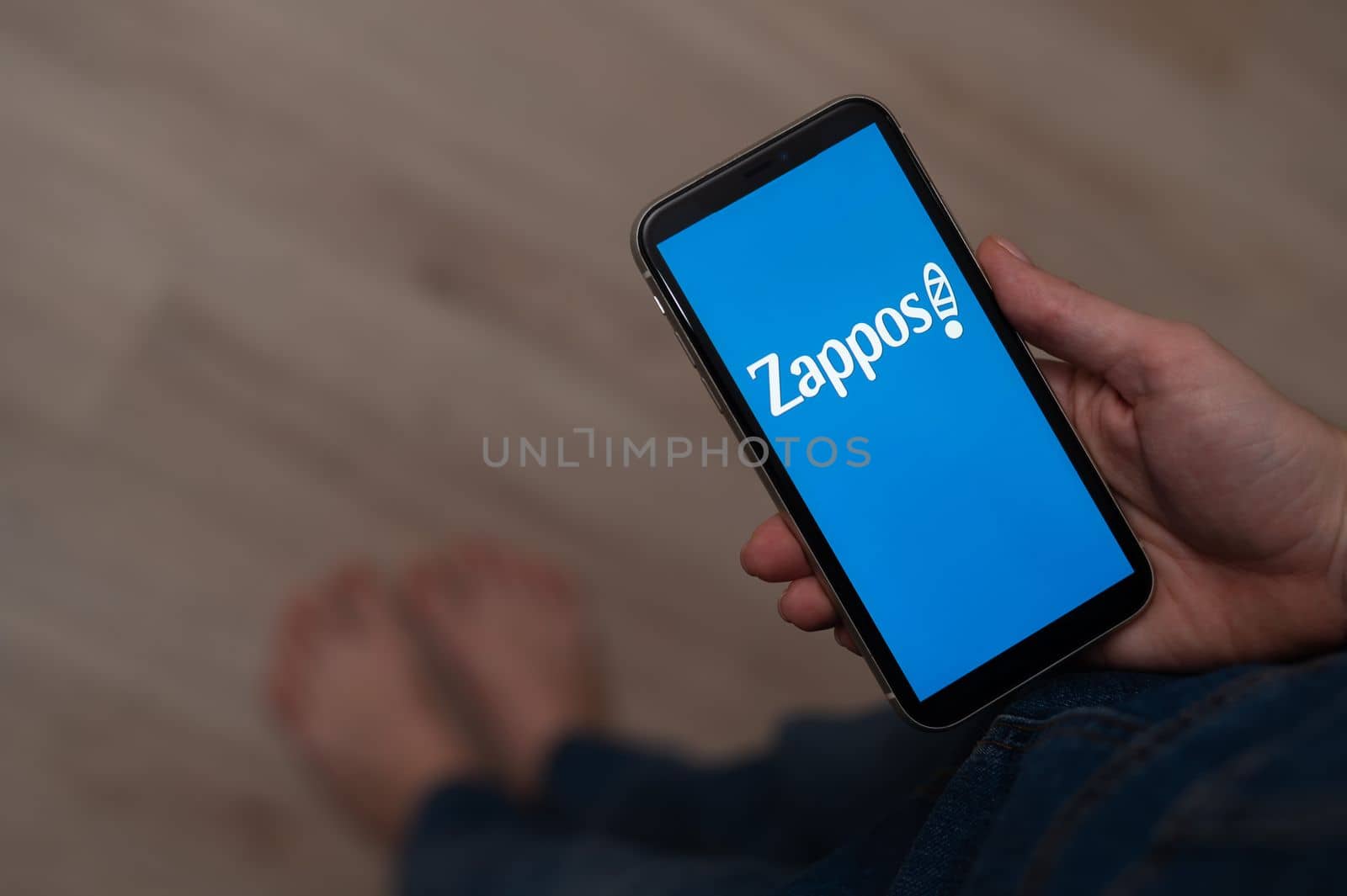 December 3, 2022 Almaty Kazakhstan: Barefoot woman holding smartphone with zappos logo