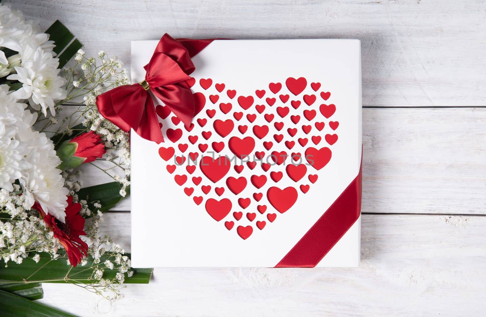 Valentine's day gift, red heart praline box and flower bouquet on white wooden table. High quality photo