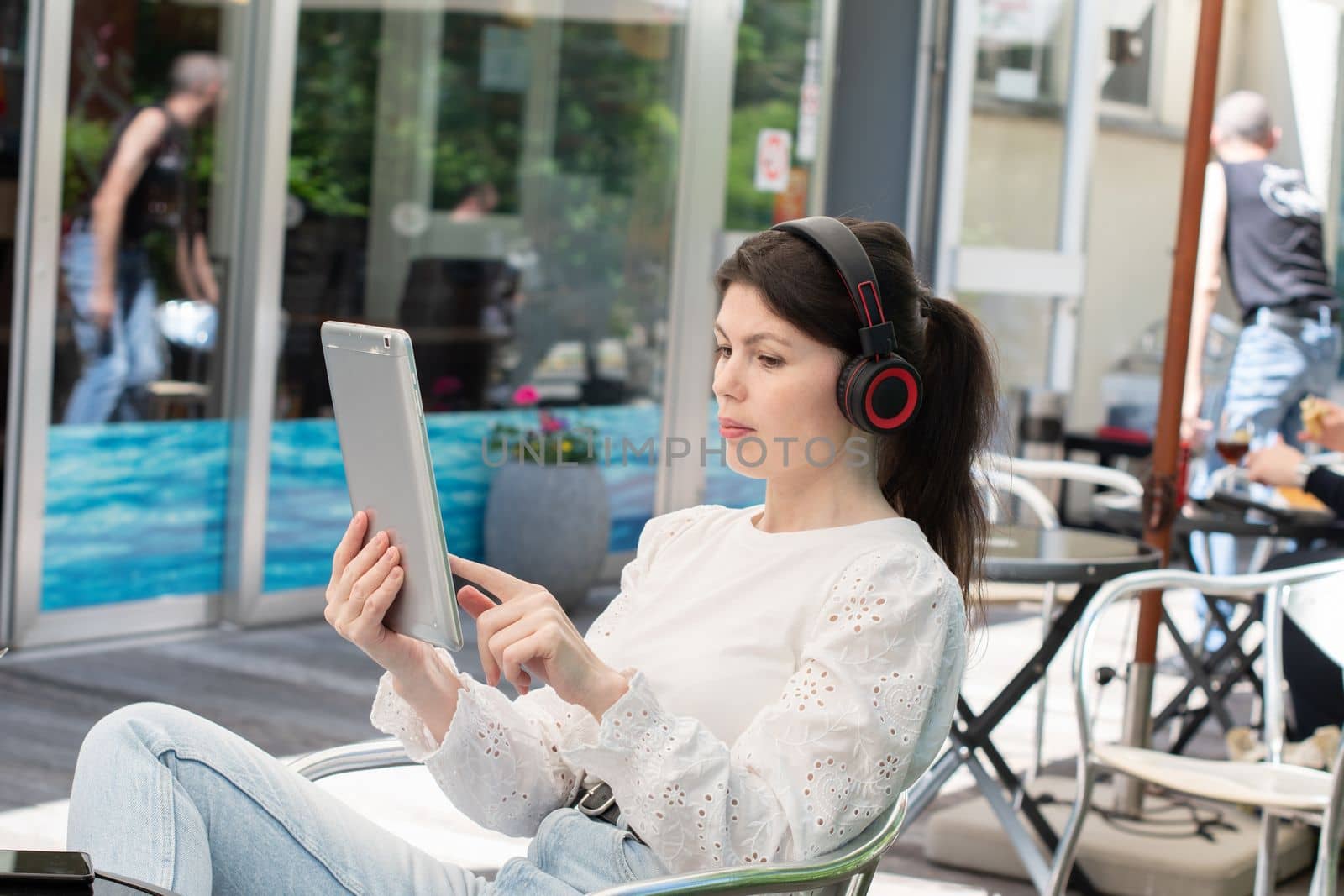 Sad girl listens to music from a tablet at a table in a cafe, High quality photo