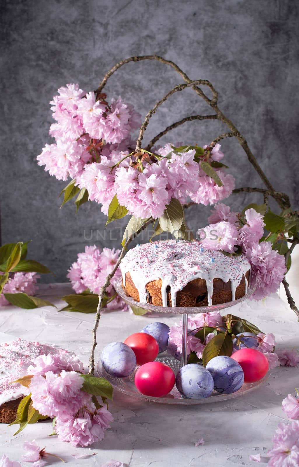 beautiful Easter cake on the table, and colored eggs, homemade cakes, still life with a silver teapot on a background of pink sakura. High quality photo