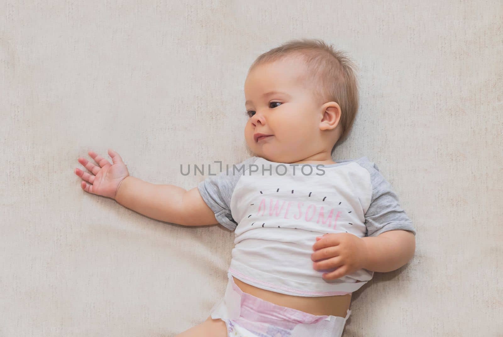 beautiful baby in a diaper is lying on the bed.