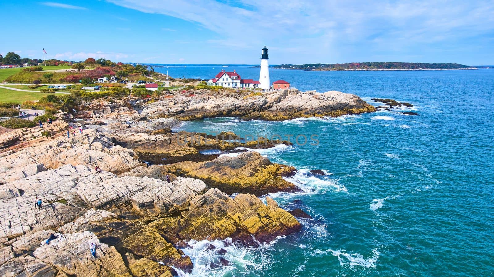 Image of Lighthouse rests on stunning rocky Maine coastline from aerial view