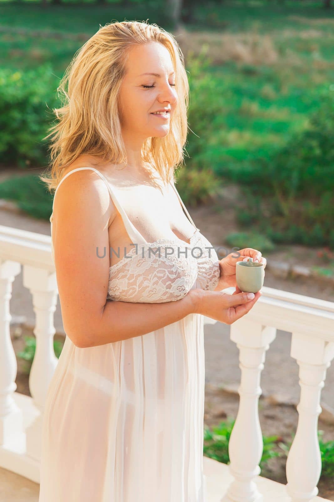 beautiful blonde in a nightgown drinking coffee on the porch at dawn.
