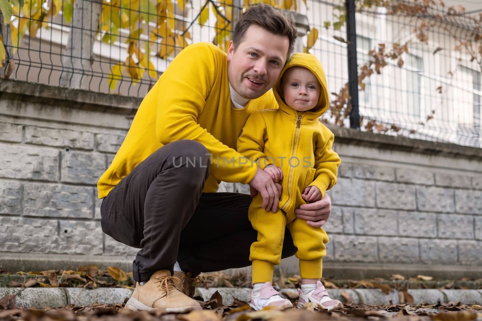 happy father holding his baby daughter smiling walking outdoor on autumn day