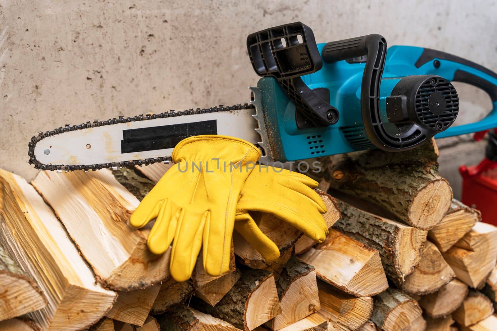 Close-up of a chain saw. electric chain saw and protective leather work gloves on the background of sawn tree trunks. lots of firewood. Firewood harvesting, forest clearing