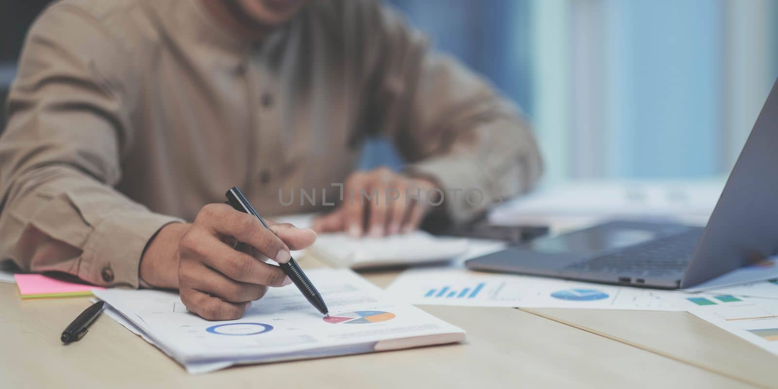 Close-up of the hands of a businessman using a calculator to check financial accounts check the company's expenses and budget. by wichayada