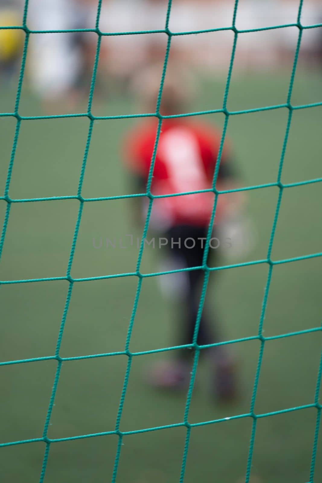 Close up rear view of a blurred goalkeeper behind the goal net