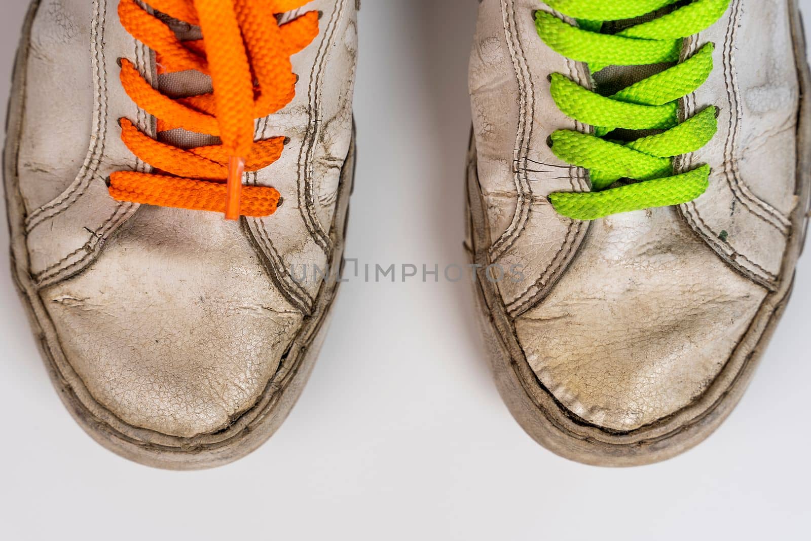 worn old torn white sneakers with colored laces on a white background by audiznam2609