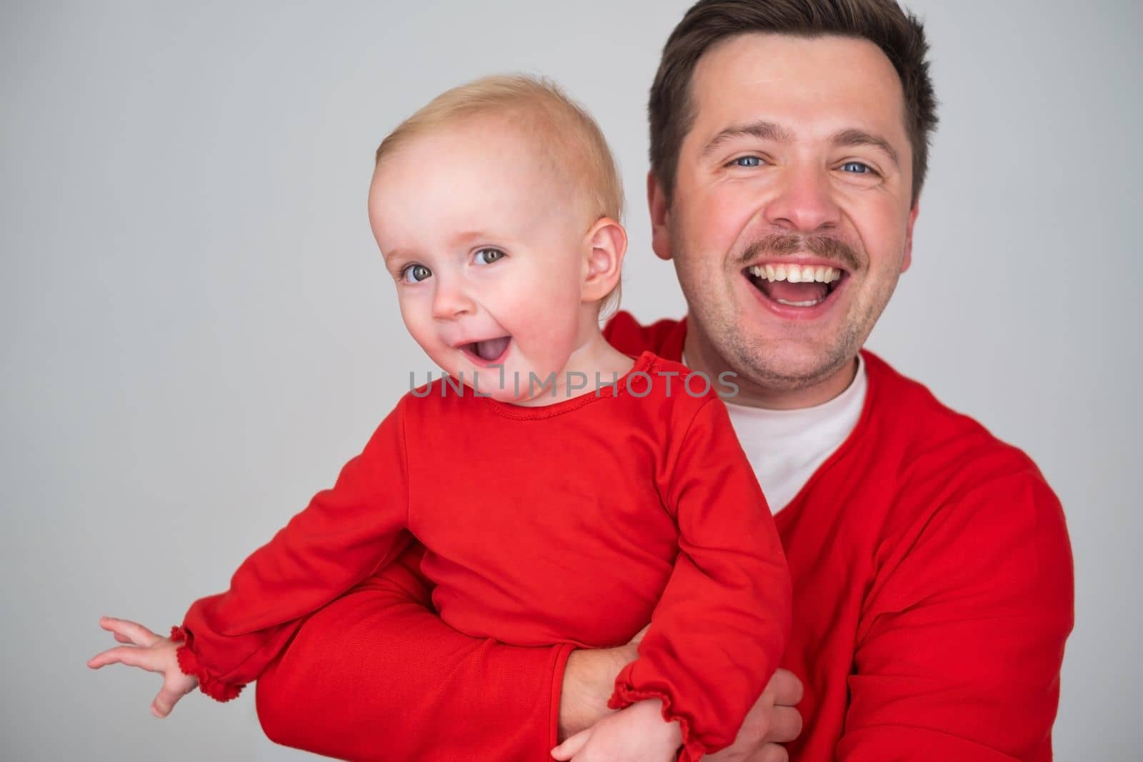 happy father holding his baby daughter smiling at camera. Studio shot