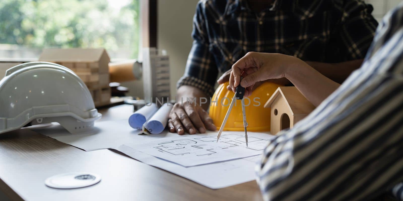 Architect team working with blueprints for architectural plan, engineer sketching a construction project, green energy concept.