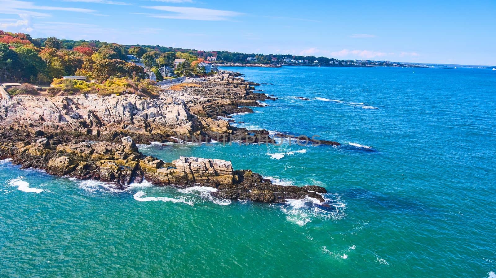 Aerial over ocean with rocky Maine coastline covered in homes by njproductions