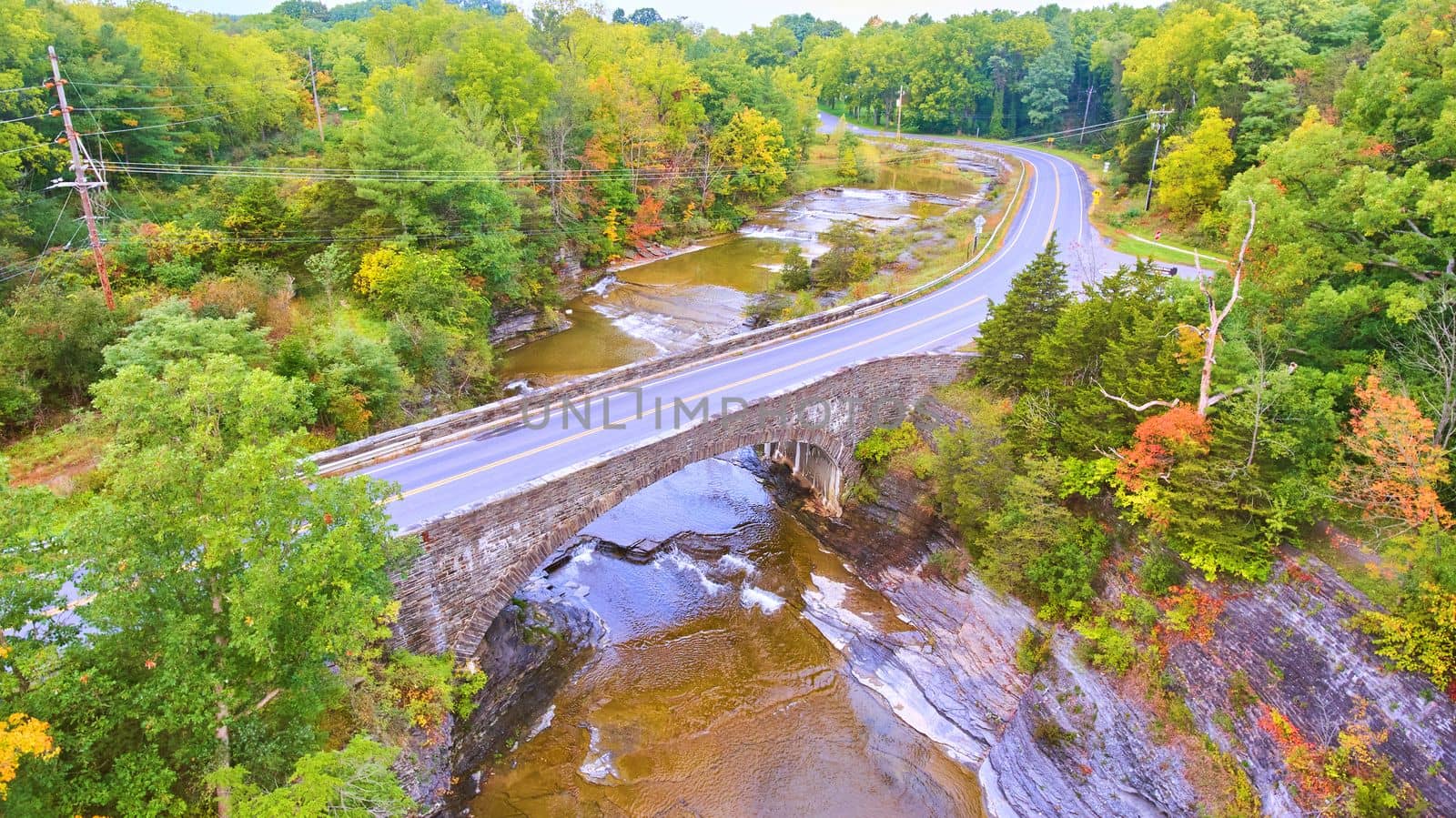 Image of Stone bridge road crosses over bridge in New York fall forest