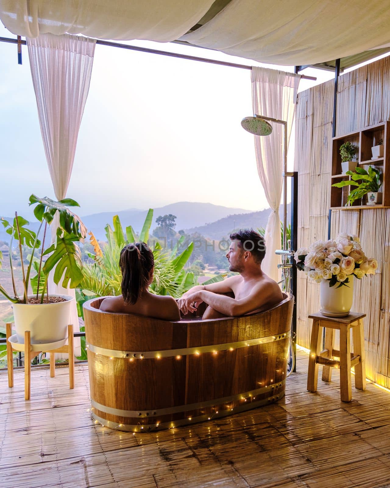 A couple of men and women in a bath tub in the evening during sunset, couple in bathtub by fokkebok