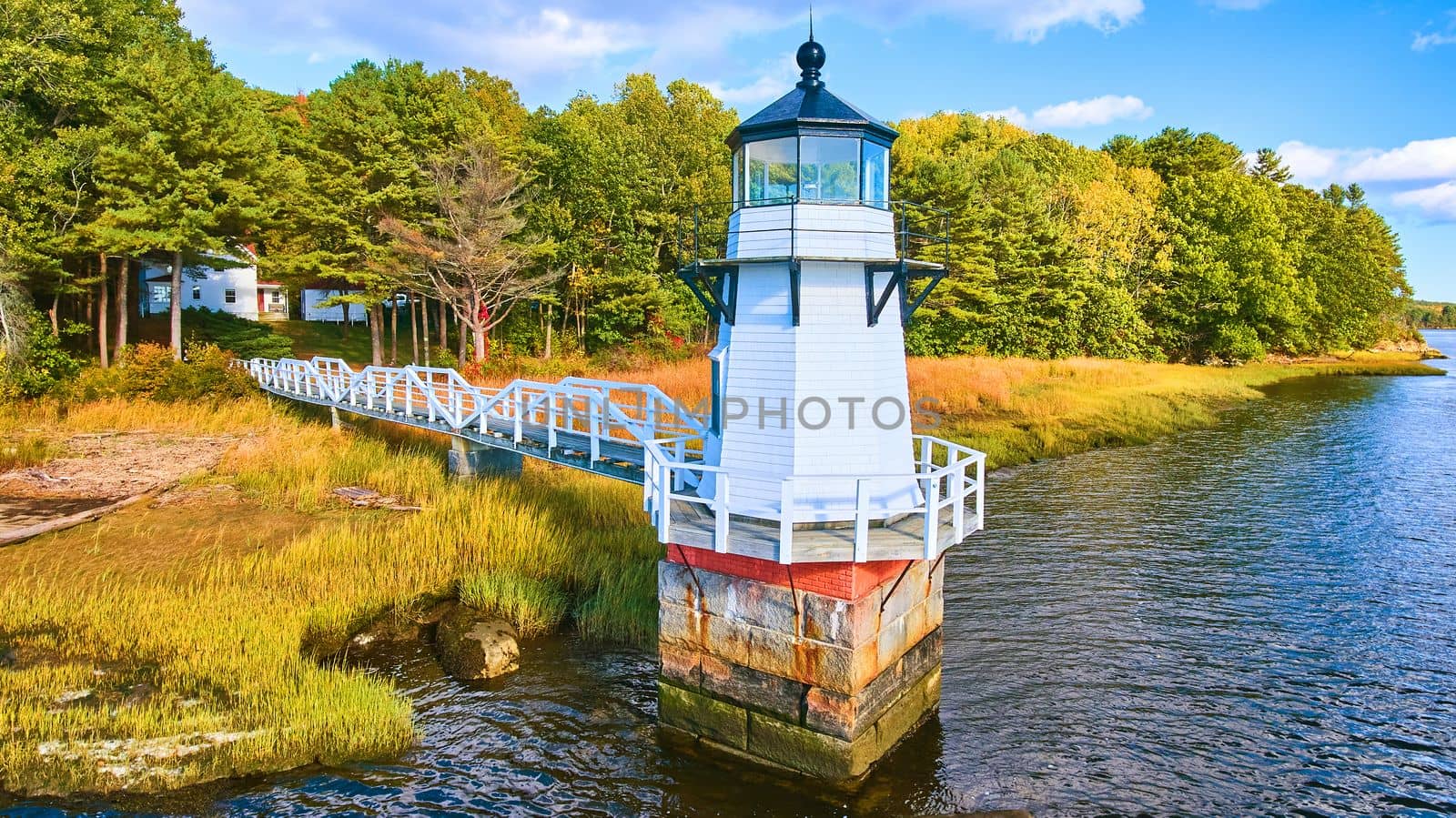 Image of Adorable tiny lighthouse on Maine coast with walkway and fall foliage