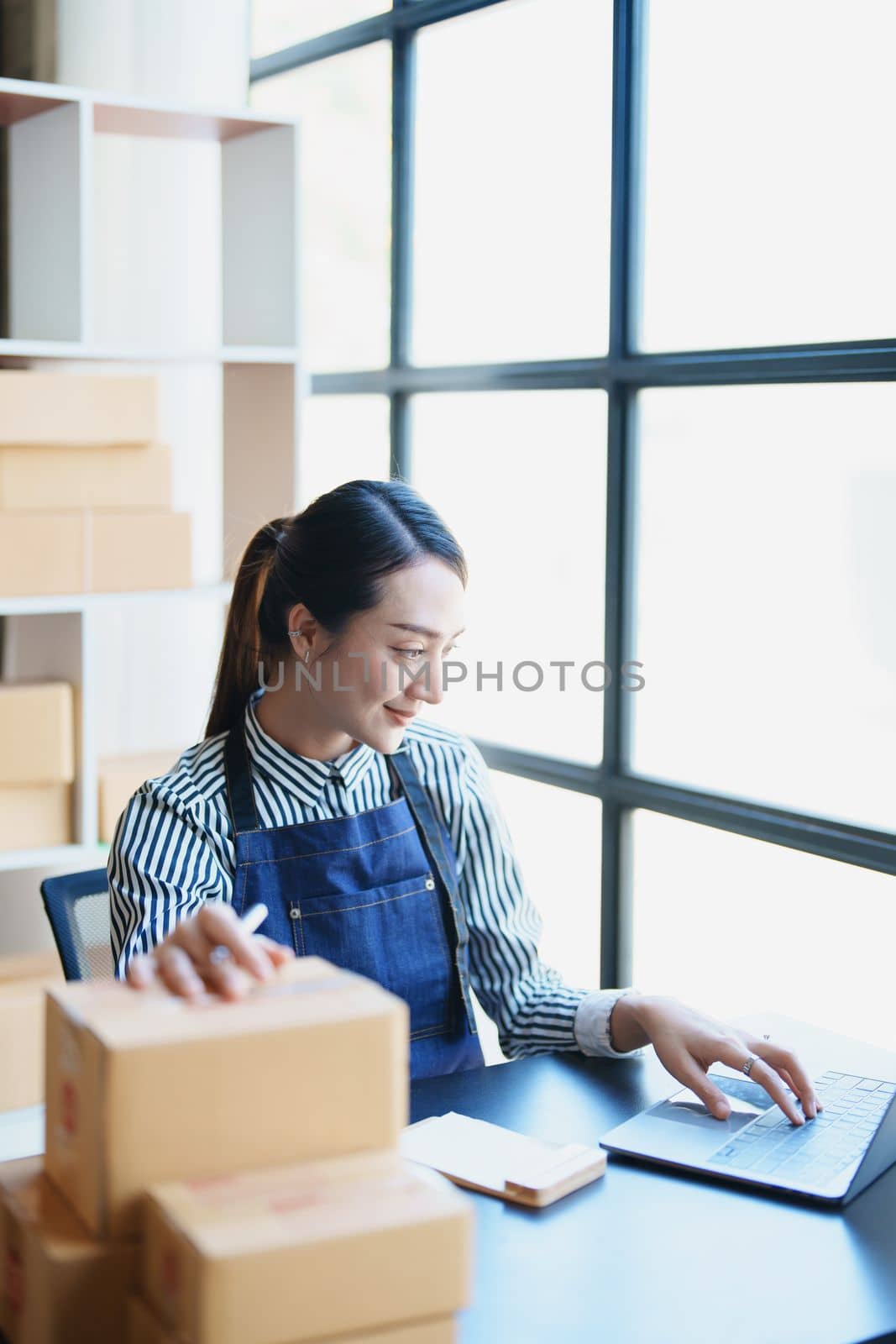 Starting small business entrepreneur of independent Asian female online seller packing products to send to customers and SME delivery concept.