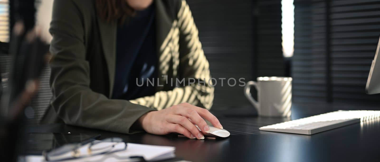 Cropped shot of female entrepreneur hand using computer mouse while working at her workstation.