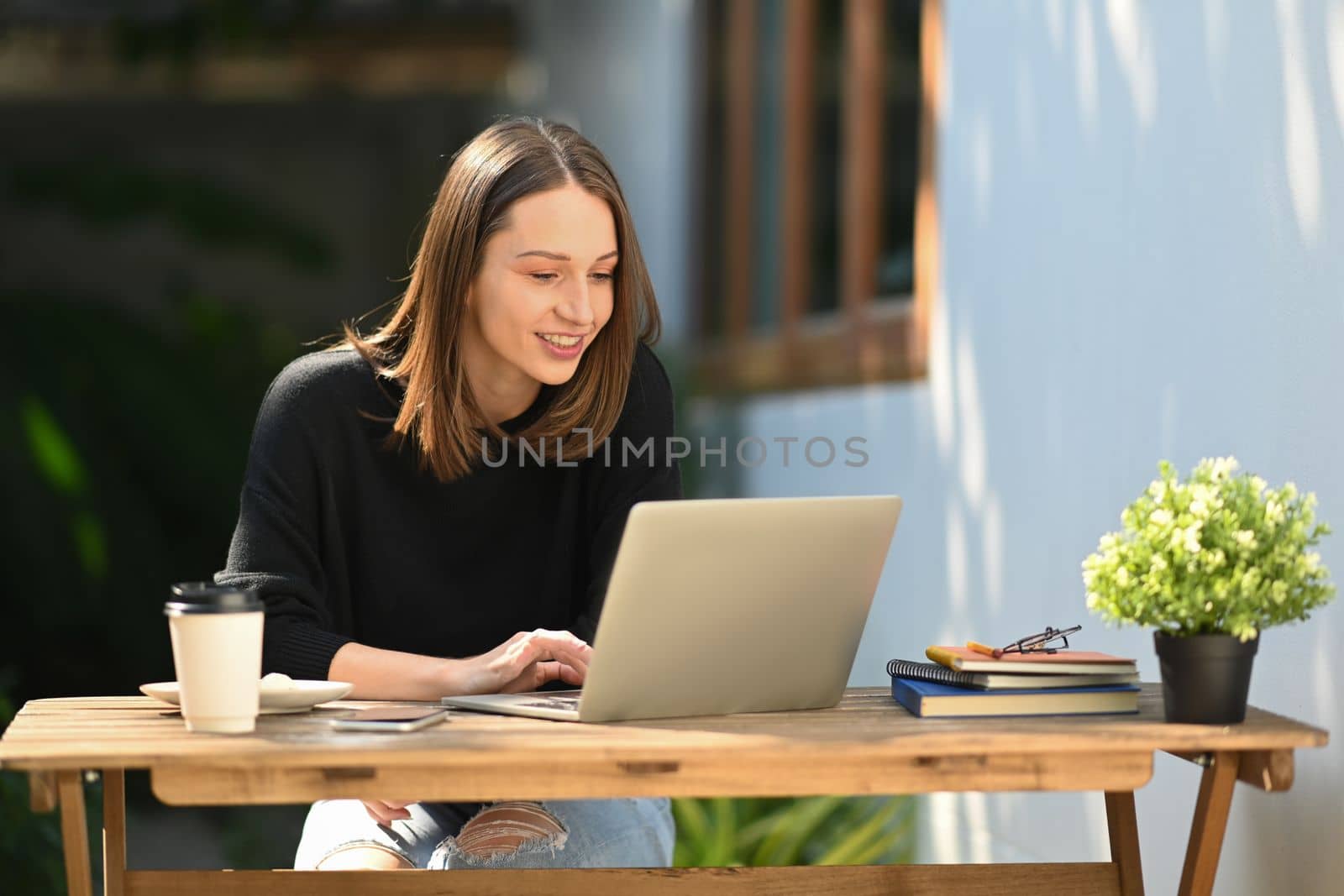 Beautiful caucasian woman having remote work on laptop computer while sitting at outdoors by prathanchorruangsak