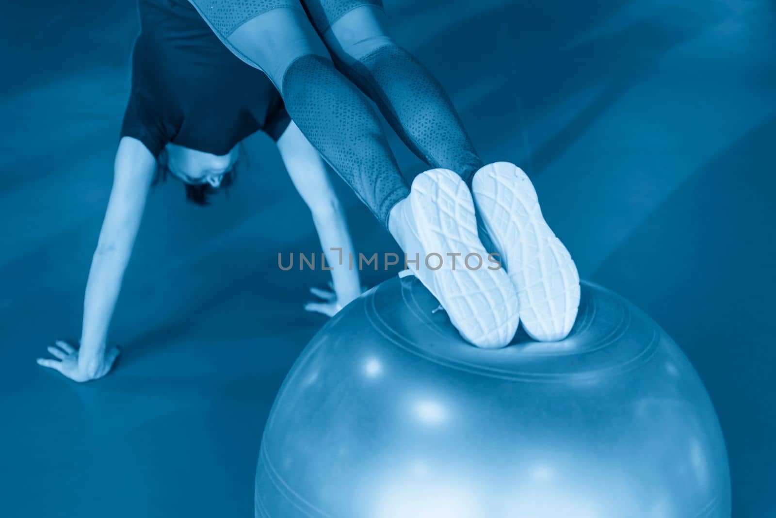 Woman at the gym doing exercises with her legs on pilates ball by Mariakray