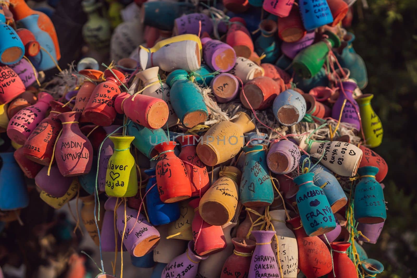 Wish tree. Small multi-colored jugs with inscriptions, wishes hanging on the branches of a tree., against the backdrop of sand ruins and blue sky by galitskaya