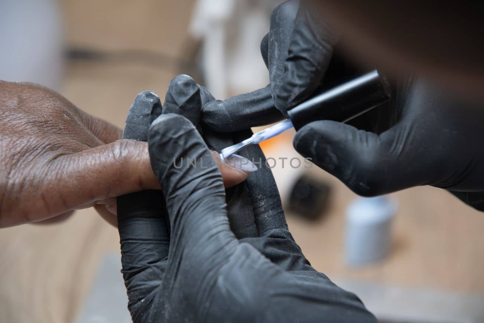 Manicurist covers the nails of a dark-skinned girl with blue gel polish in a beauty salon, High quality photo
