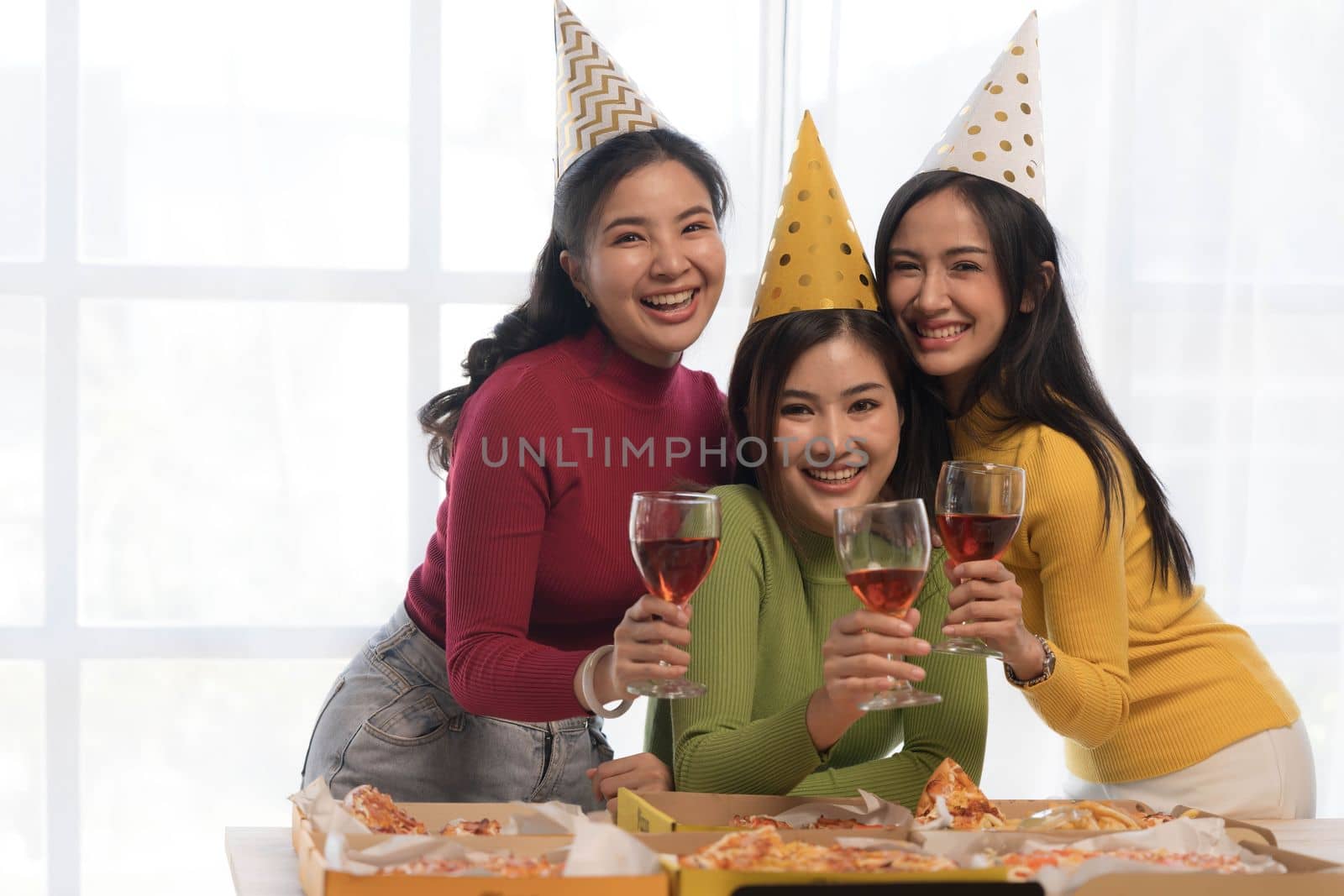 Group of happy young Asian people with friends celebrating clinking glasses during dinner party by wichayada