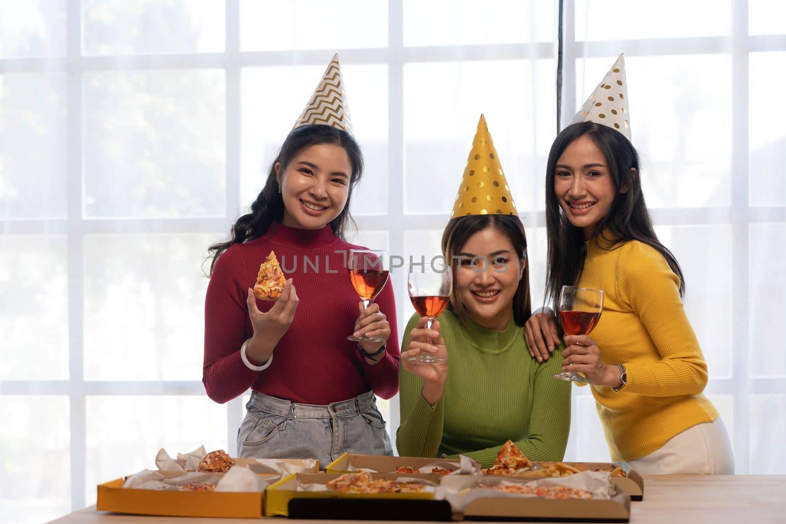 Group of happy young Asian people with friends celebrating clinking glasses during dinner party.