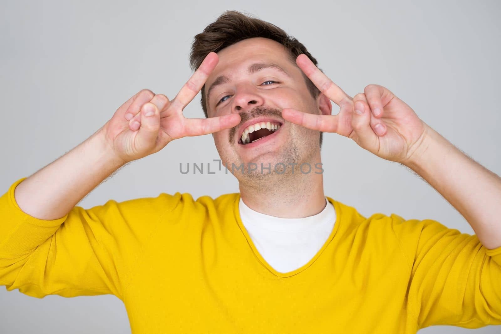 Young handsome man showing fingers doing victory sign. Number two. 