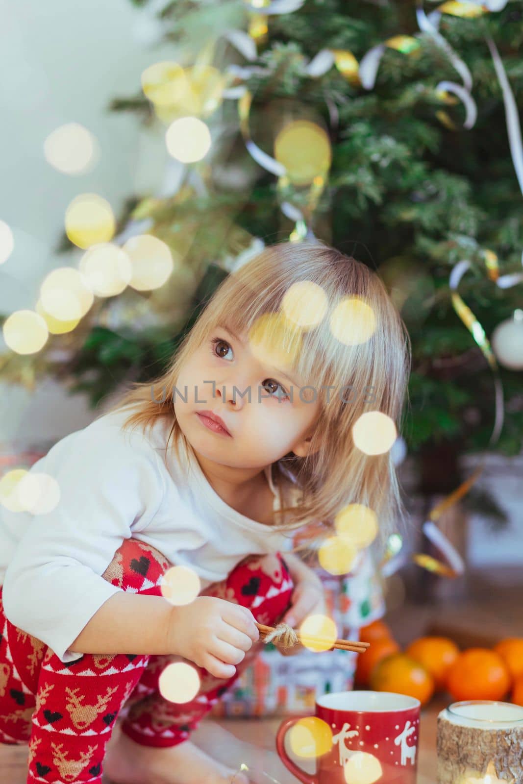 Charming child playing near the christmas tree.