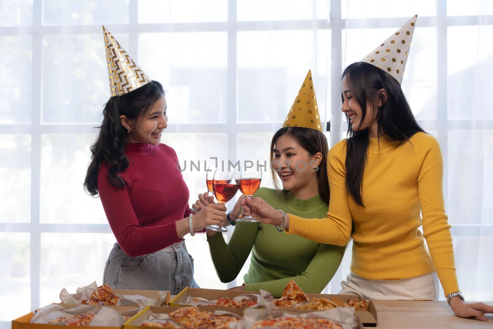 Group of happy young Asian people with friends celebrating clinking glasses during dinner party.