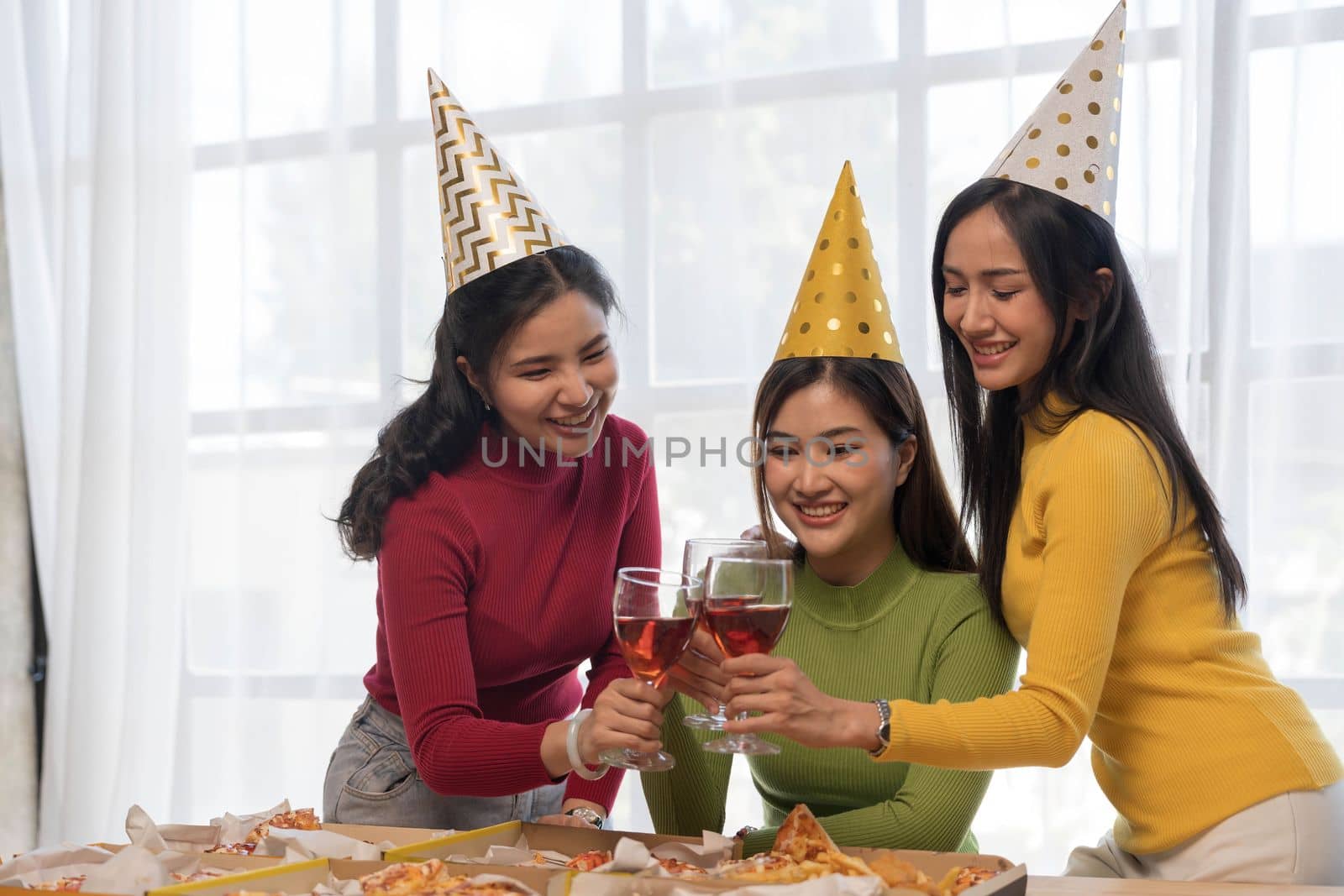 Group of happy young Asian people with friends celebrating clinking glasses during dinner party by wichayada