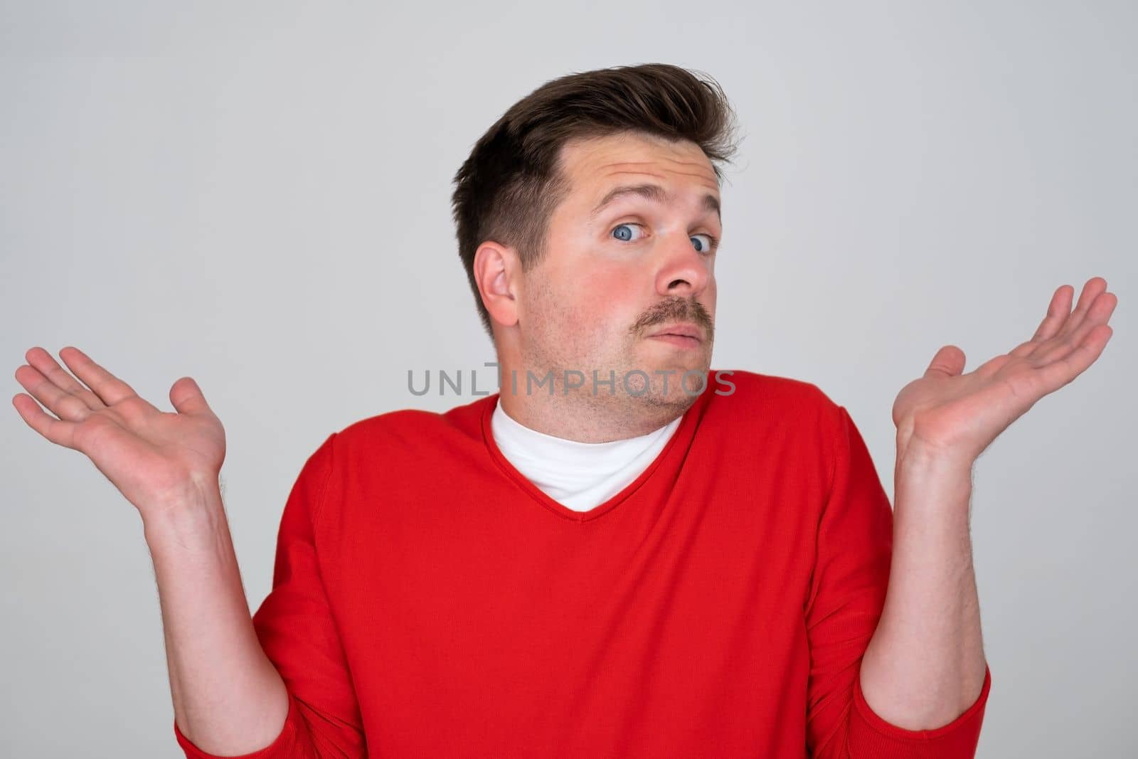 Puzzled caucasian man with arms outstretched looks to the camera doesn't know what to do 