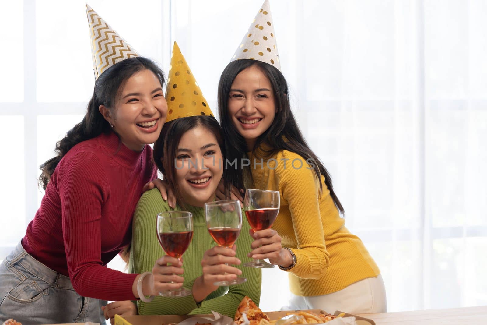 Group of happy young Asian people with friends celebrating clinking glasses during dinner party.